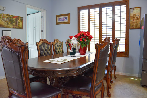 A beautifully arranged dining room featuring a wooden table surrounded by elegant chairs, complemented by decorative flowers and natural light from the windows.