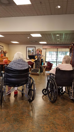 A performer entertains residents at an activity center, bringing music and joy to the elderly in wheelchairs.