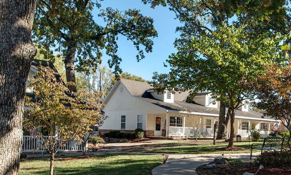 A charming house surrounded by trees and a well-maintained lawn on a sunny day.