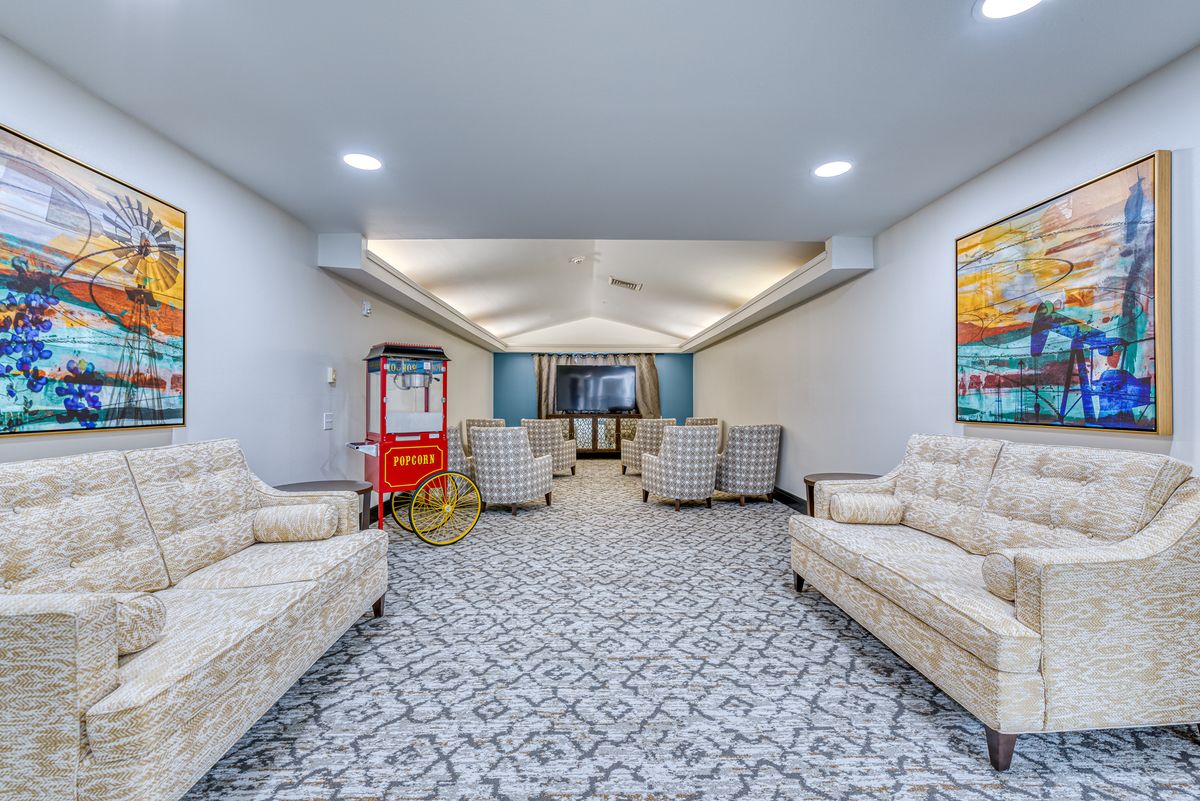 A spacious lounge area featuring comfortable seating, a popcorn machine, and a large TV screen.