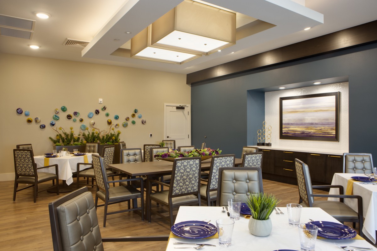 A modern dining room with neatly arranged tables and chairs, featuring contemporary decor and lighting.