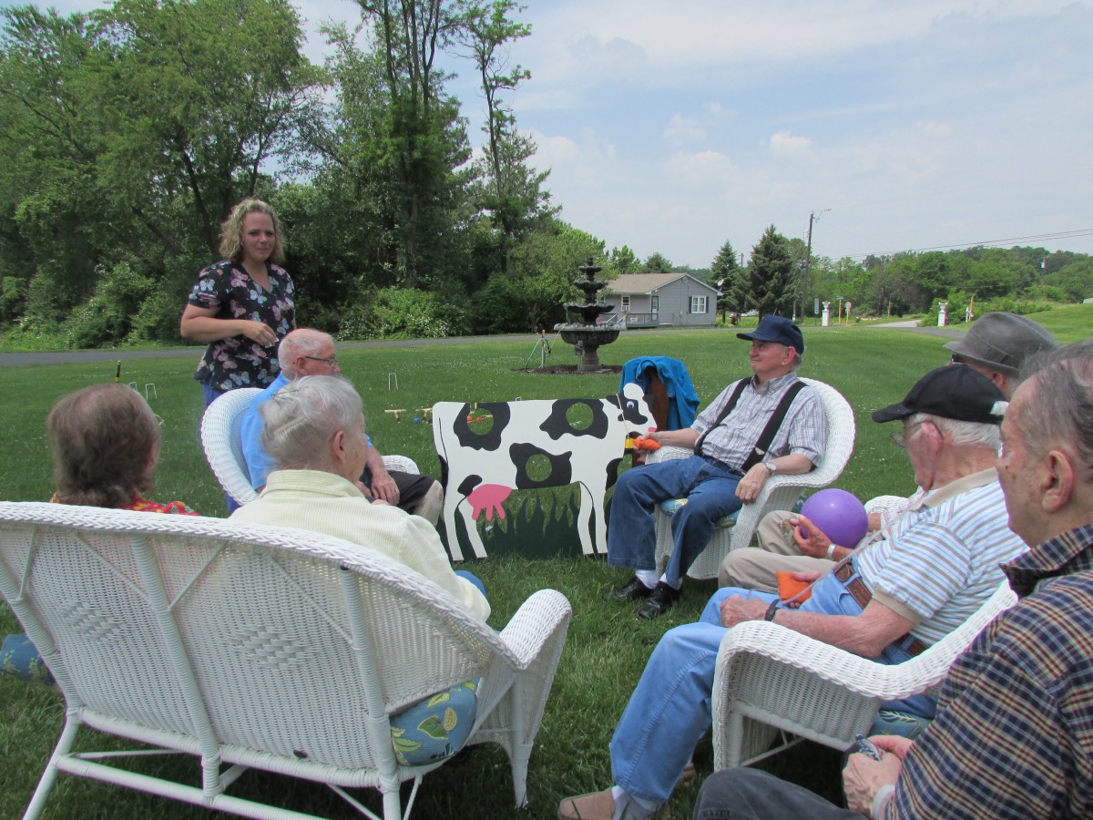 A group of people sitting in a circle outdoors, having a conversation in a garden setting.