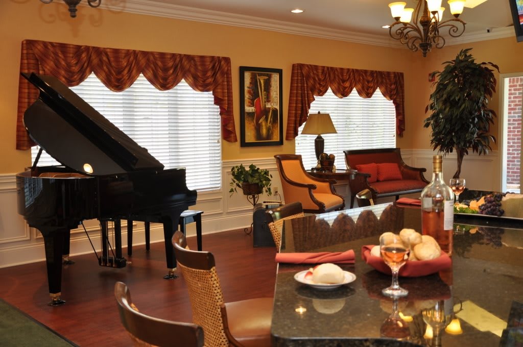 A stylish living room featuring a grand piano, elegant furniture, and warm lighting.