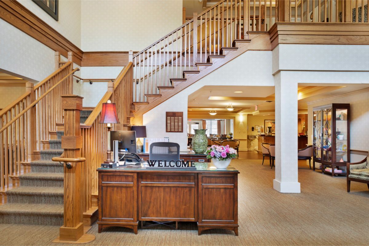 A welcoming reception area with a wooden desk and a staircase in the background.