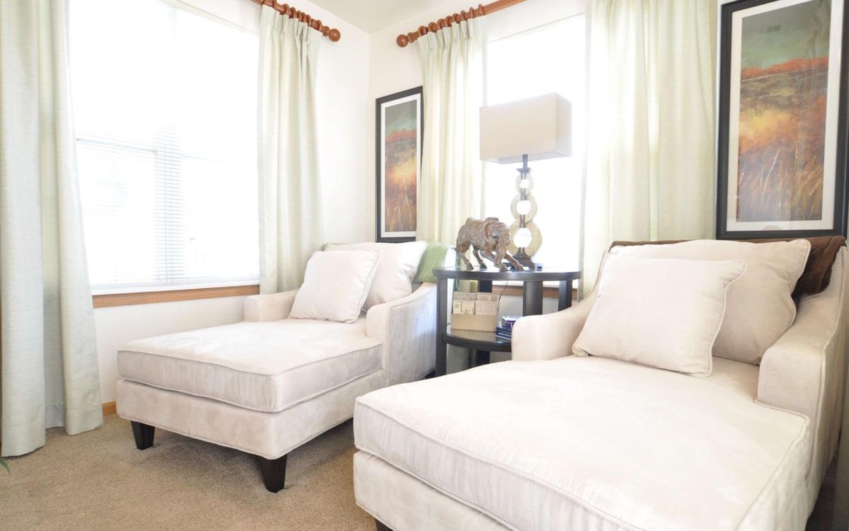 A cozy living room with elegant armchairs, a side table, and soft lighting.