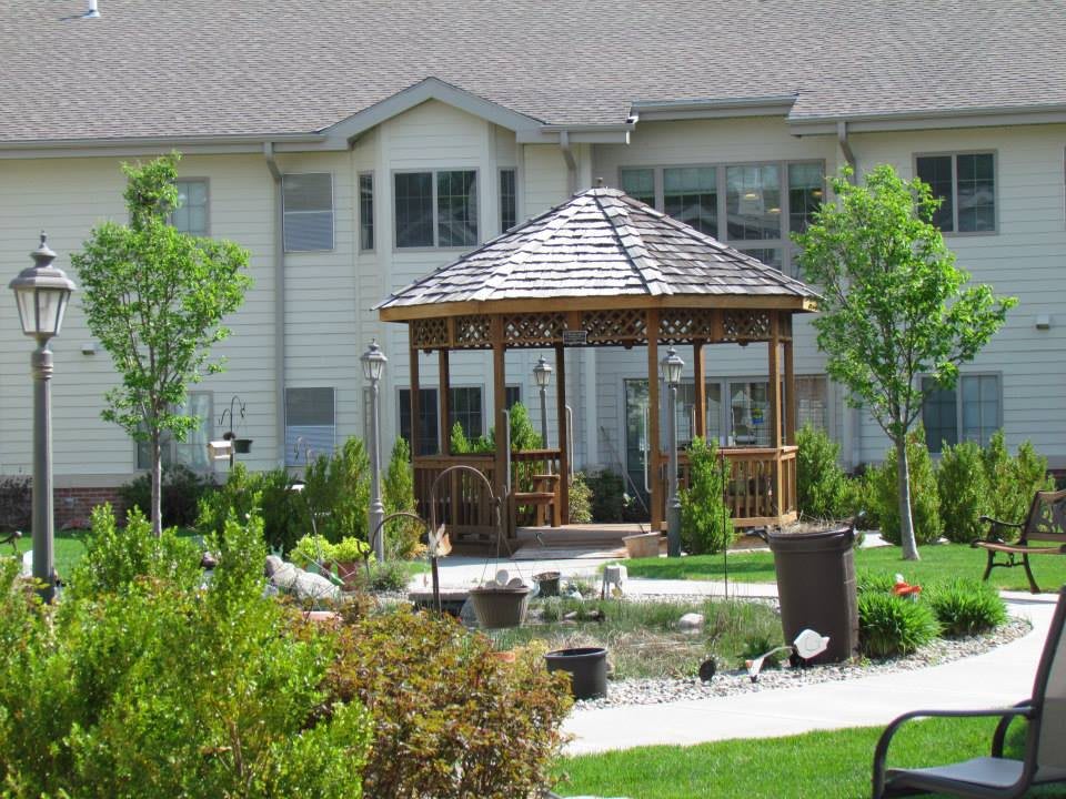 A well-maintained garden featuring a wooden gazebo in front of a residential building.