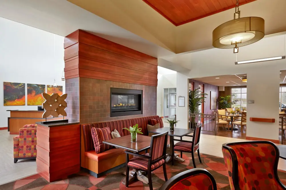 A modern hotel lobby featuring a cozy seating area with a fireplace, accented by contemporary decor and comfortable furniture.
