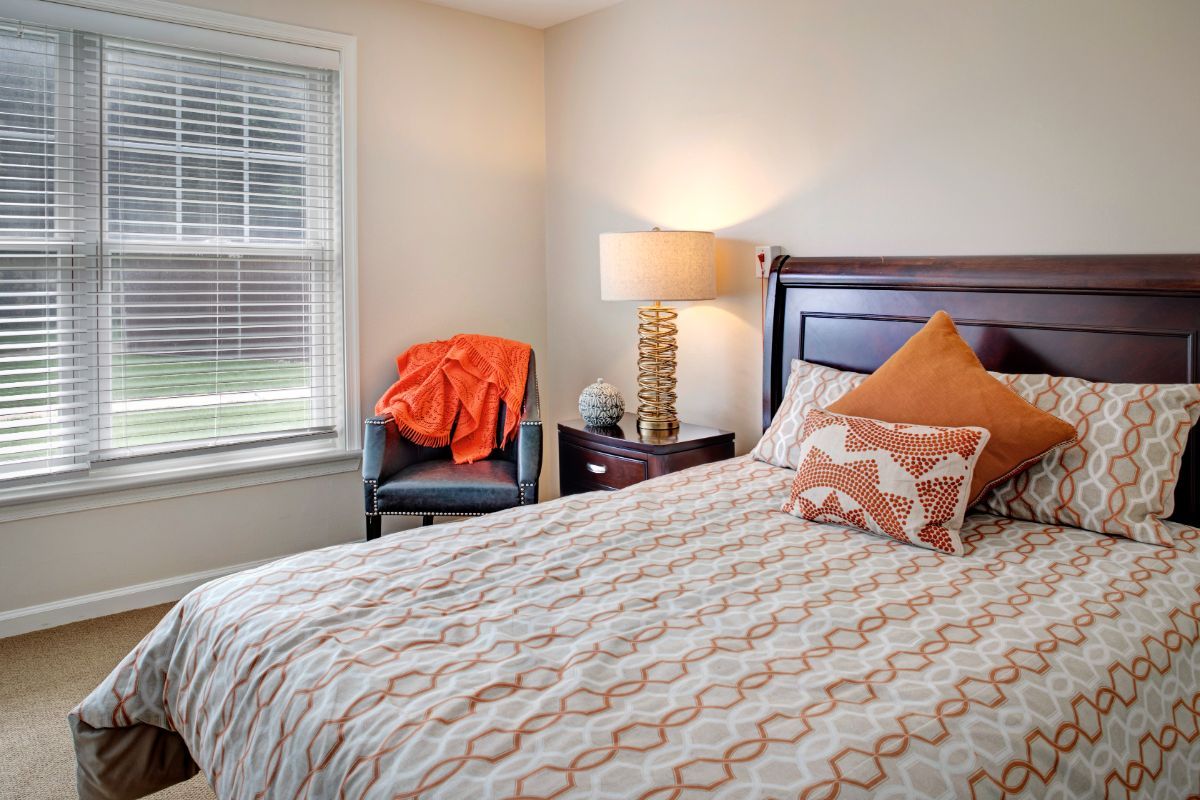 A cozy bedroom with a patterned bedspread and orange accents.