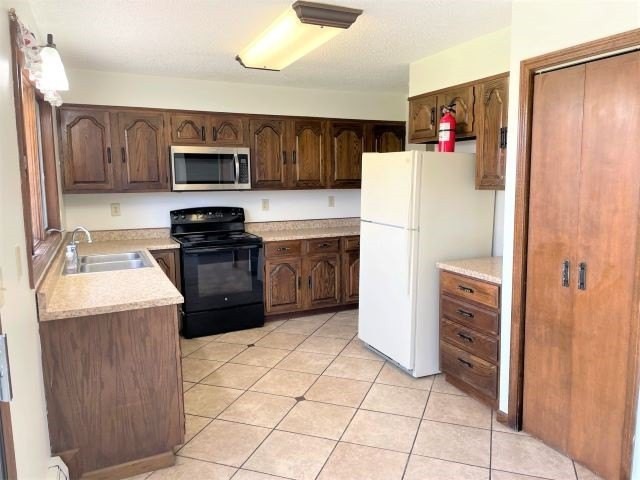 A kitchen with wooden cabinets, a stove, microwave, and refrigerator.