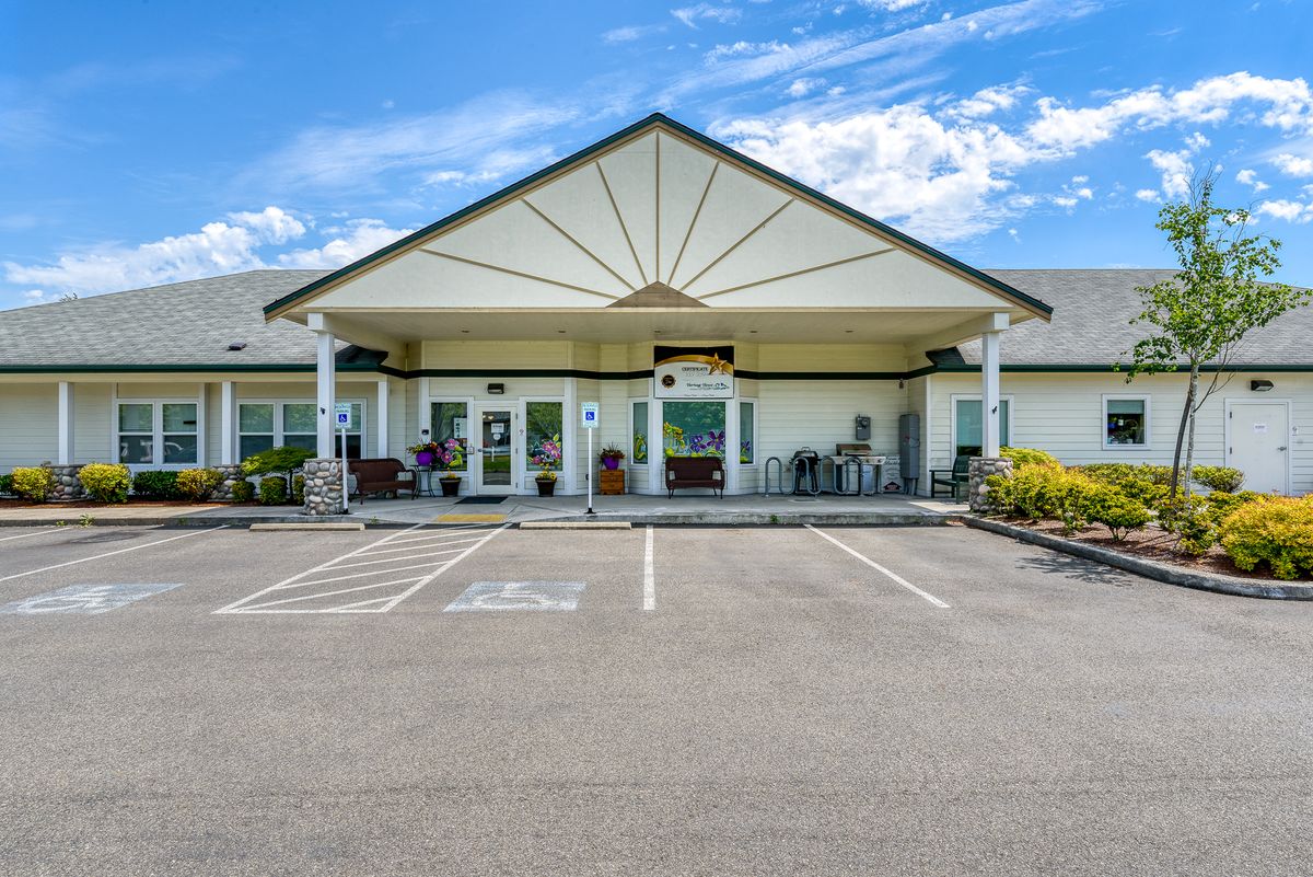 A building with a prominent entrance and an adjacent parking lot under a partly cloudy sky.