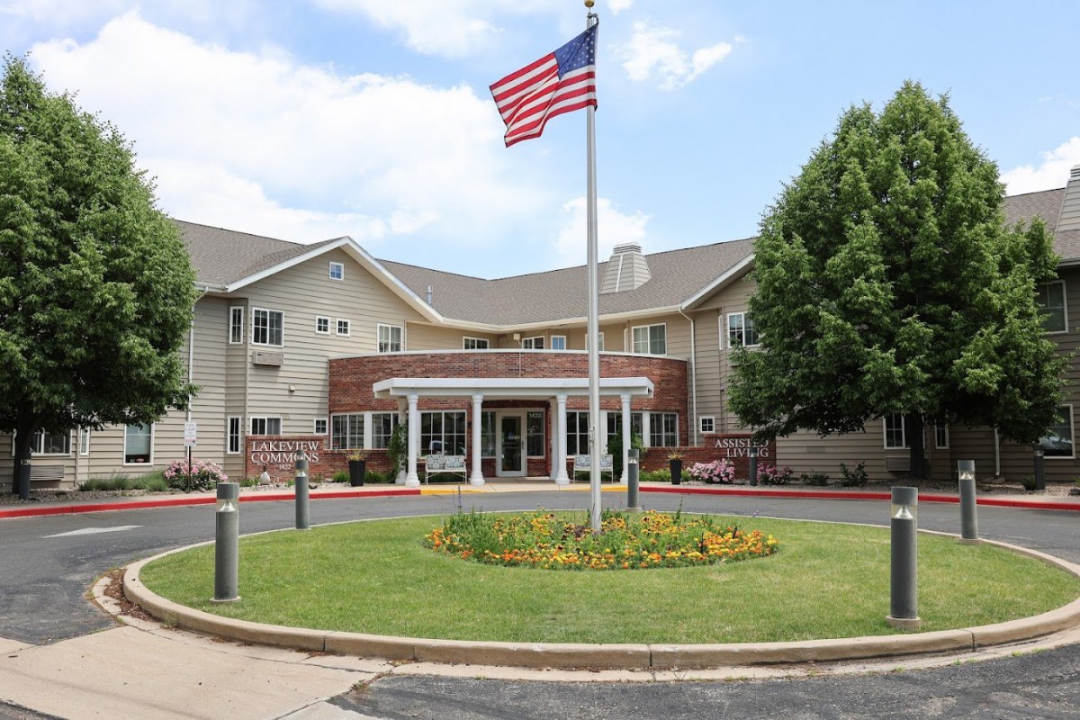 A large building with an American flag flying in front, surrounded by well-maintained landscaping and trees.