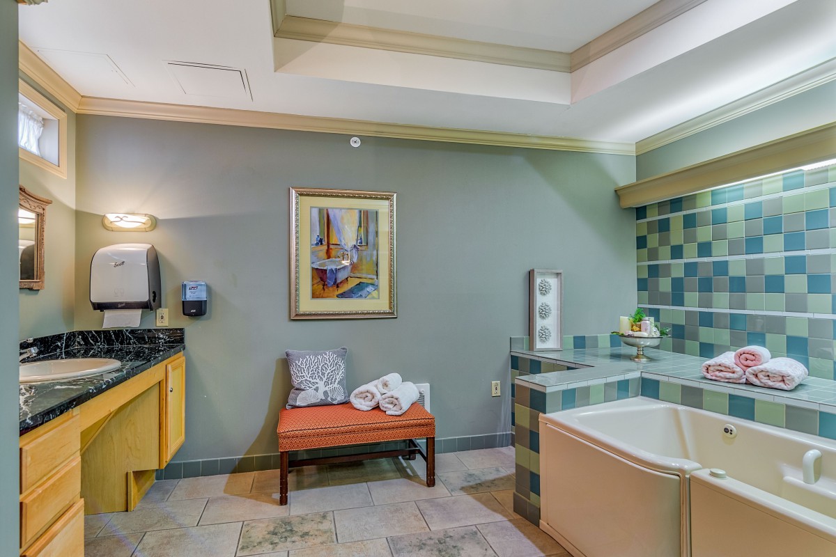 A modern bathroom with a bathtub, decorative painting, and a bench.