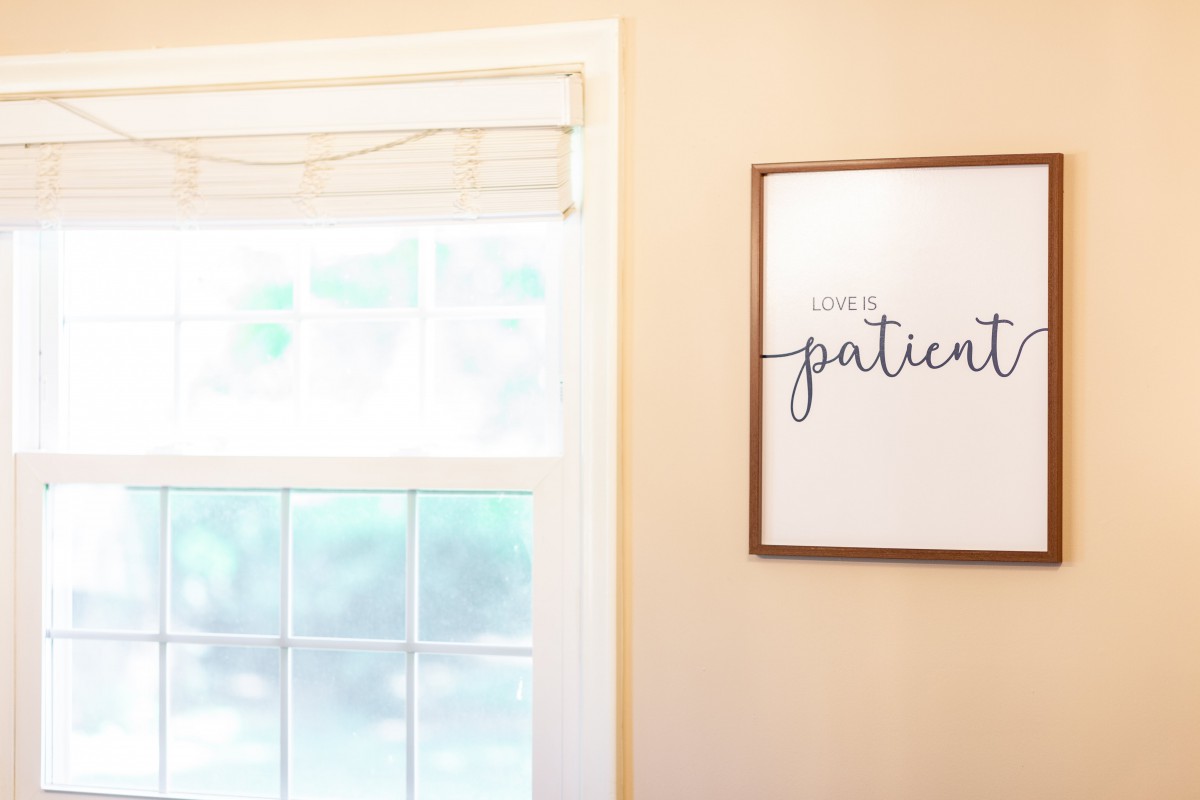 A cozy room featuring a window with soft lighting and a framed inspirational quote on the wall.