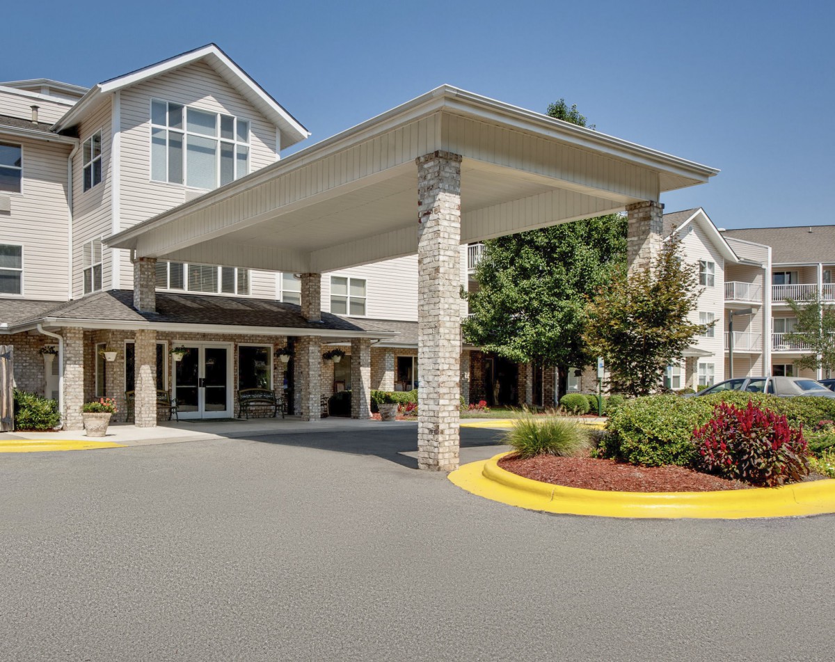 A modern building entrance with a covered driveway and landscaped surroundings.