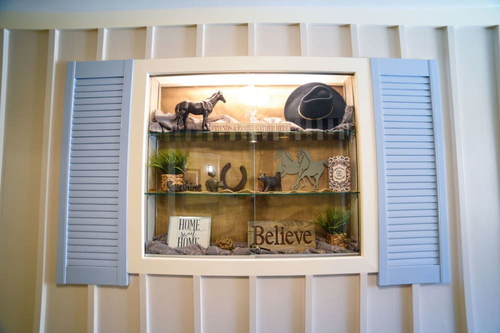 A decorative shelf display featuring a horse figurine, hat, plants, and inspirational signs.