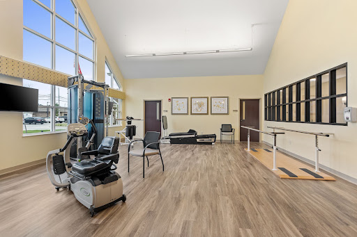 A spacious and well-lit therapy room equipped with exercise machines and rehabilitation tools.