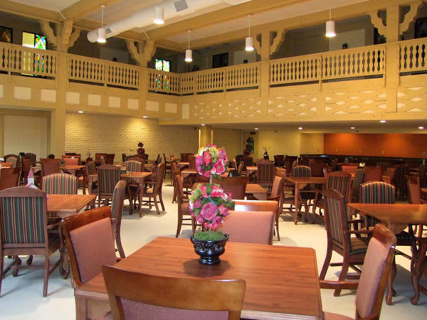A spacious dining hall with wooden tables, chairs, and floral decorations.
