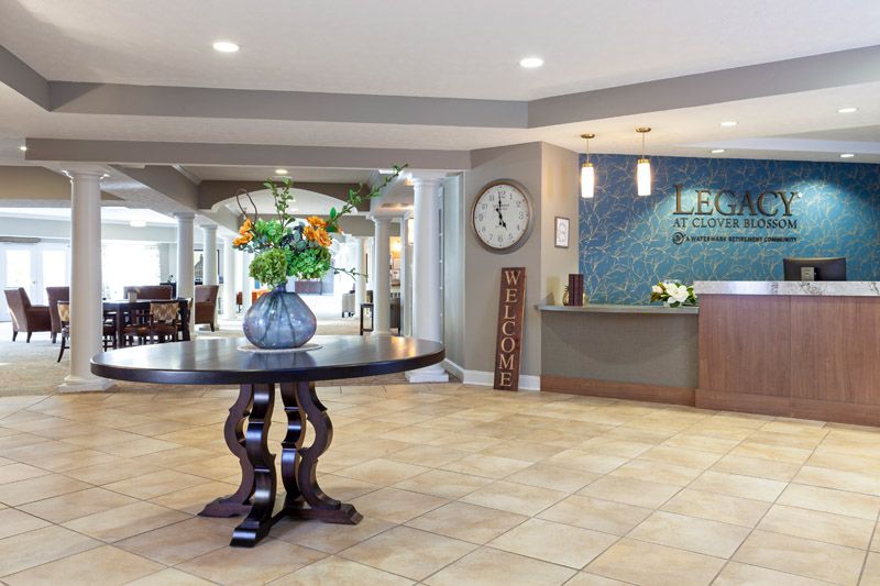 A spacious hotel lobby with a reception desk and a decorative table with flowers.