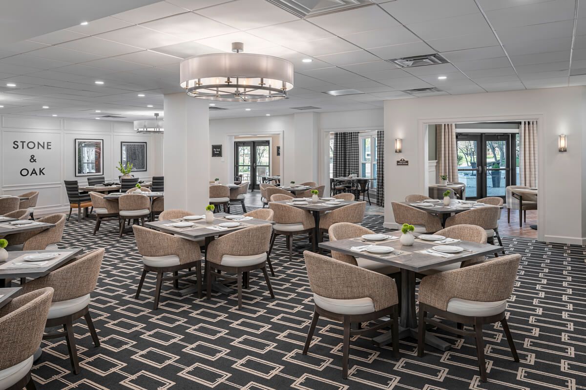 A modern dining room with neatly arranged tables and chairs, featuring contemporary decor and elegant lighting.