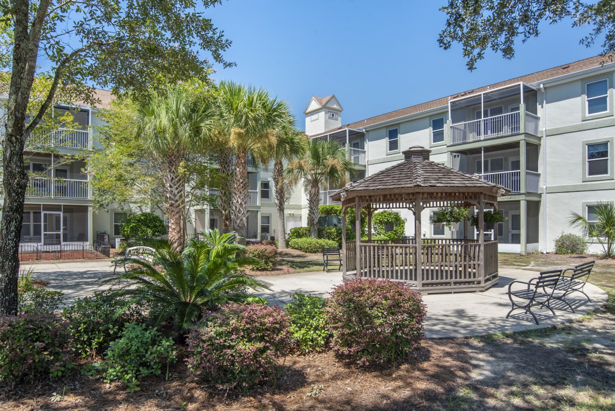 A beautiful apartment complex with a well-maintained gazebo and lush landscaping.