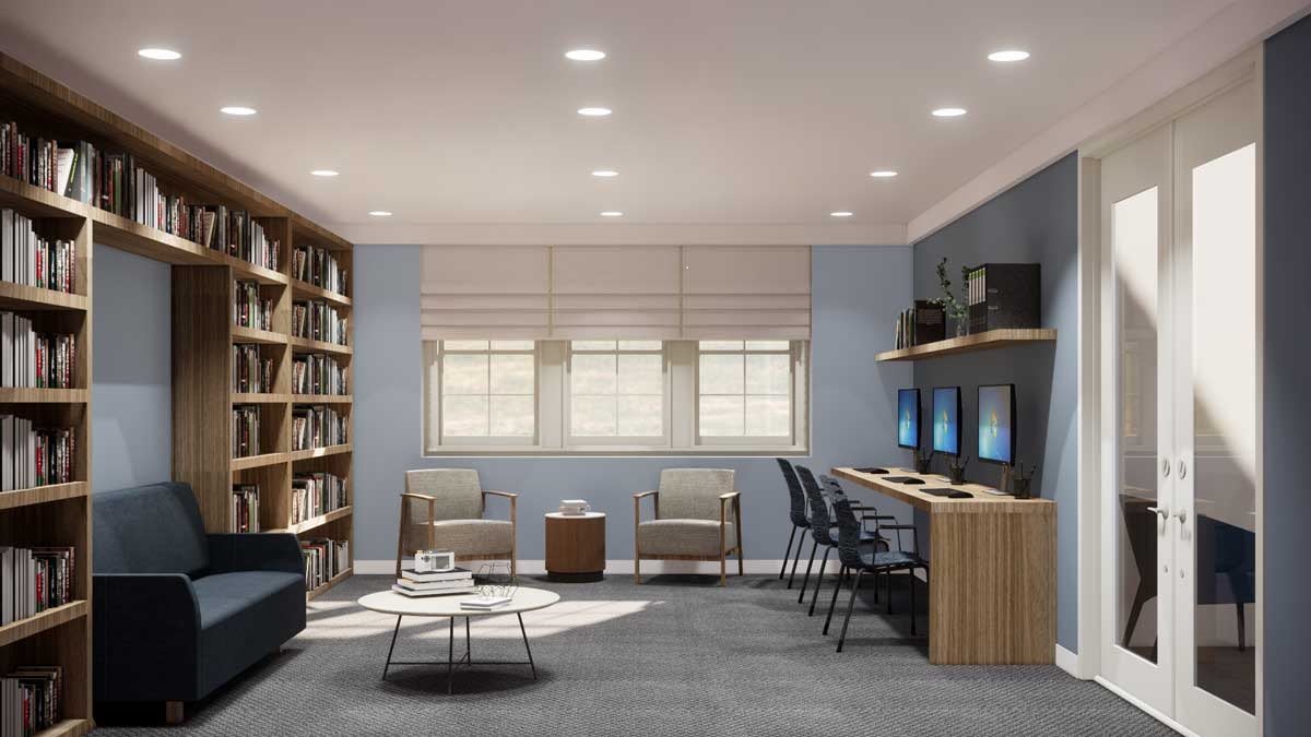 A modern office space with computers, bookshelves, and seating area.