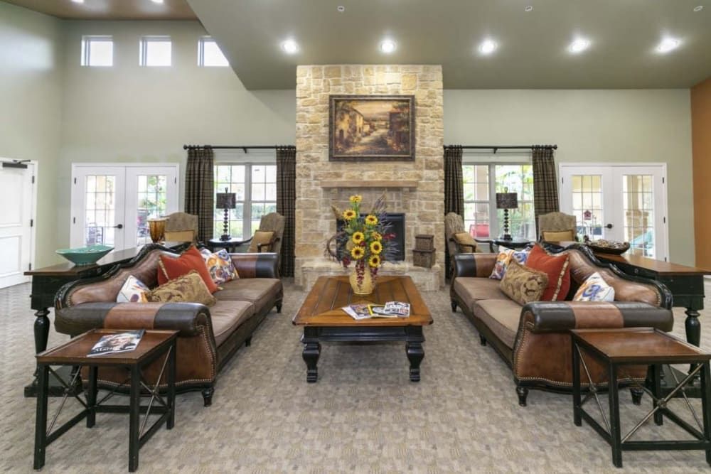 A spacious living room featuring a central brick fireplace, surrounded by elegant sofas and a coffee table adorned with sunflowers.