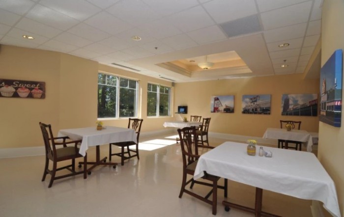A bright and airy dining area with neatly arranged tables and chairs, illuminated by natural light from large windows.