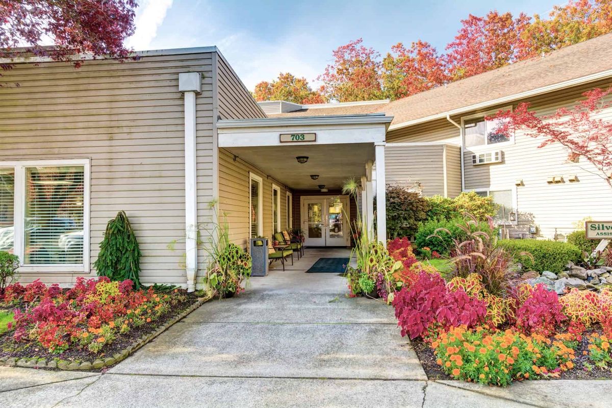 An inviting building entrance adorned with vibrant autumn foliage and well-maintained gardens.