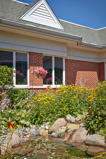 A beautifully landscaped garden surrounding a brick house with vibrant flowers.