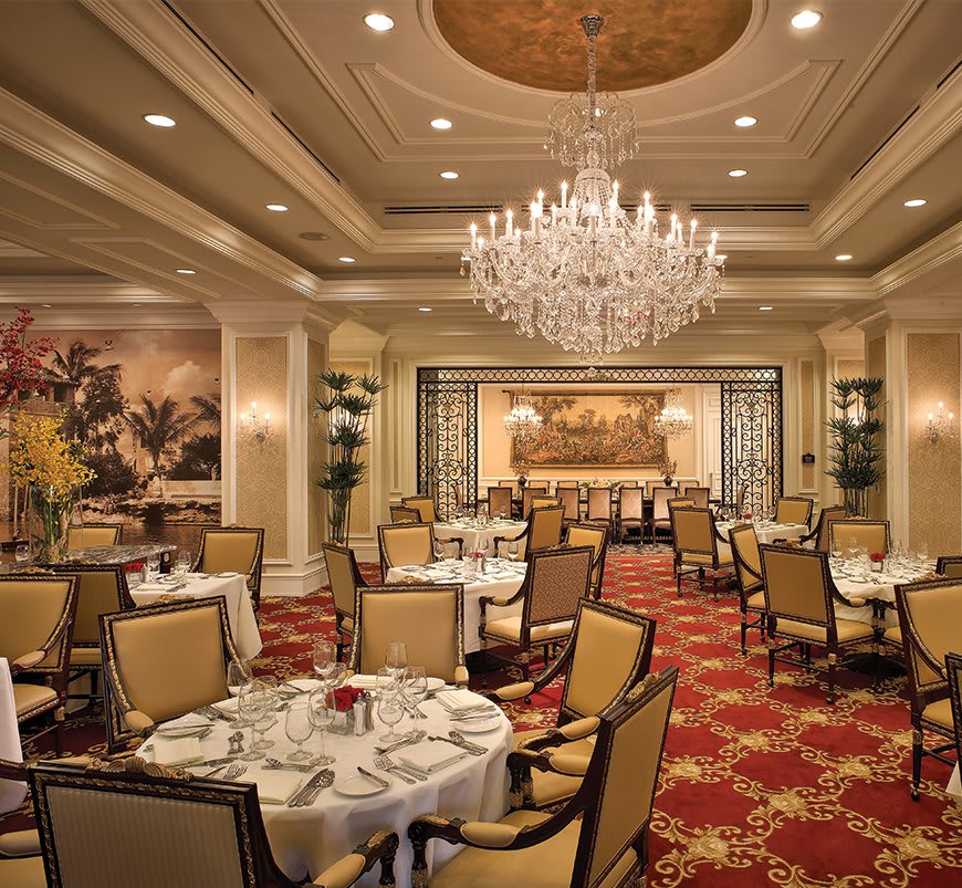 A luxurious restaurant dining room featuring elegant chandeliers and a formal setting.
