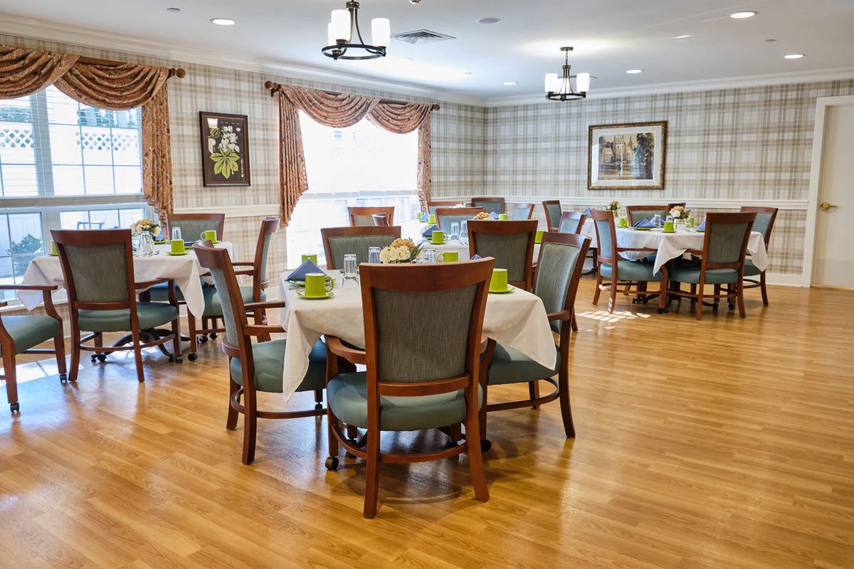 An elegantly decorated dining room with neatly arranged tables and chairs on a wooden floor.