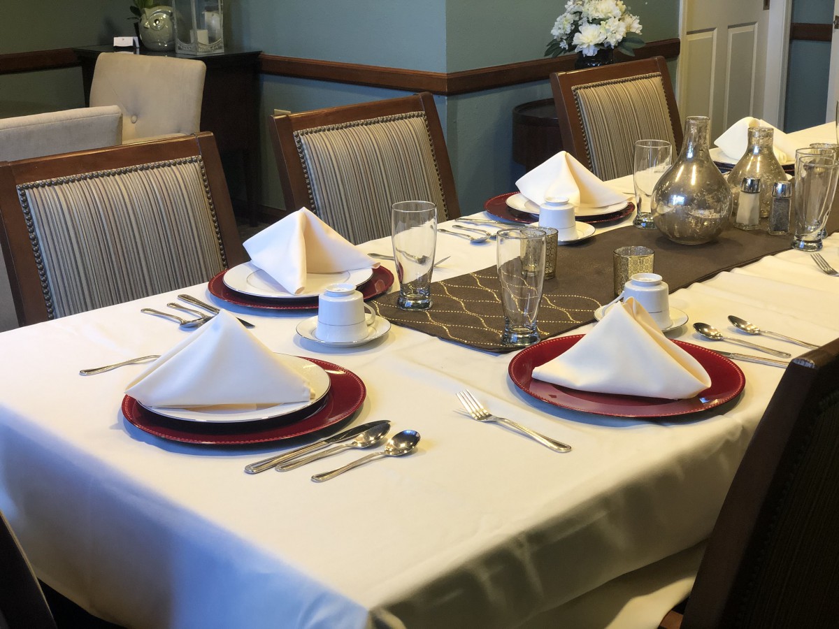 A formally set dining table with napkins, plates, glasses, and silverware.