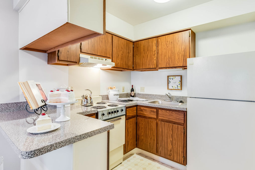A compact kitchen featuring wooden cabinets, a stove, and a refrigerator.