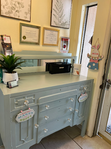 A charming blue desk set up with certificates, a plant, and office supplies.