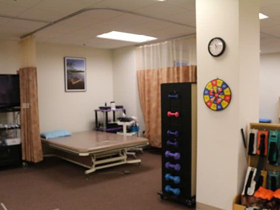 A physical therapy room equipped with exercise tools and a treatment table.