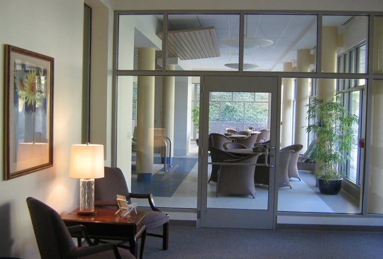 A cozy lobby area with seating and a lamp, separated by a glass door.