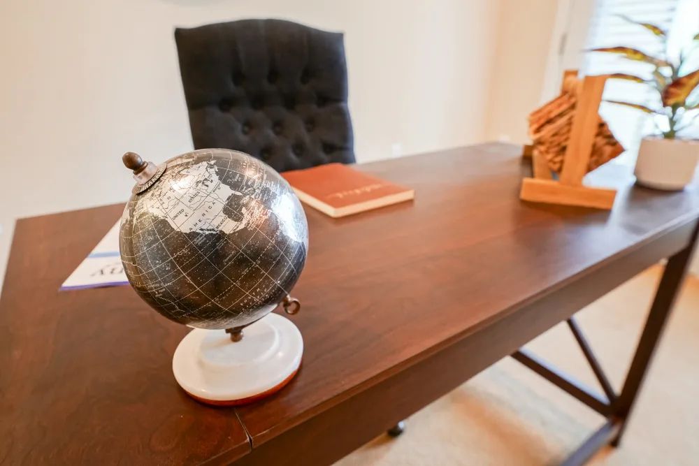 A stylish office desk with a globe, book, and decorative piece.