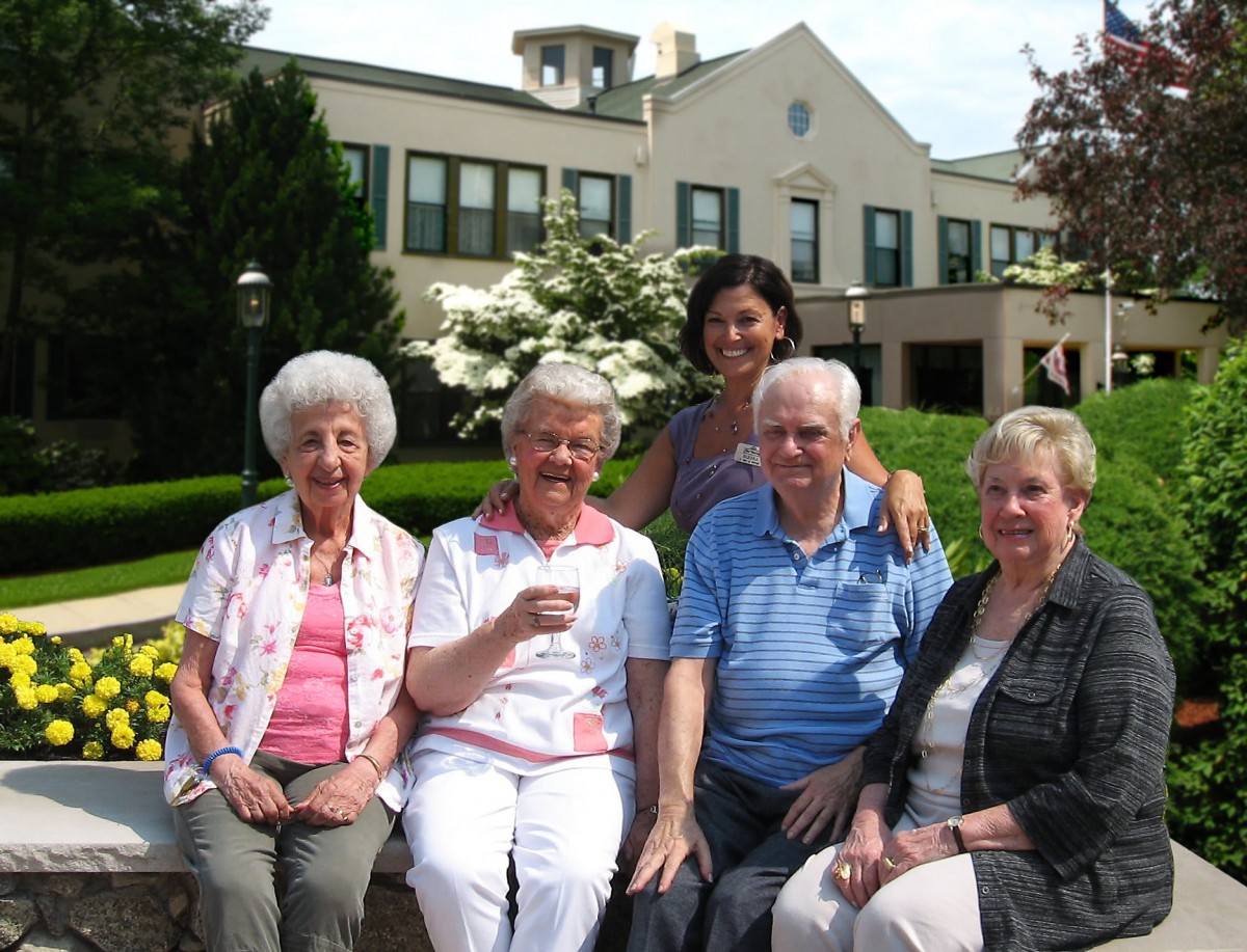 A group of seniors sitting together outdoors, smiling at the camera.