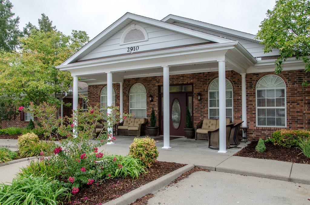 A charming house with a front porch supported by white columns and surrounded by a well-maintained garden.