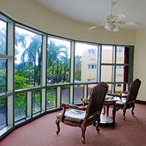 A cozy seating area with large glass windows overlooking lush palm trees.