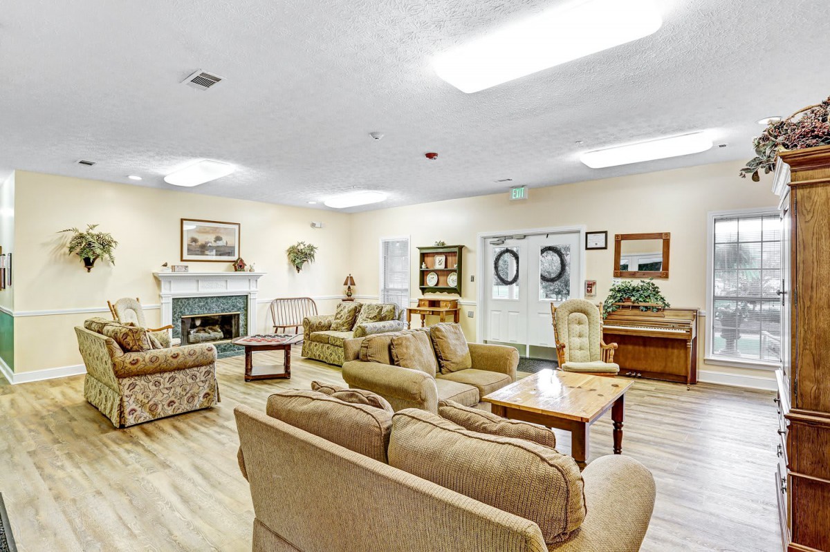 A cozy living room with multiple sofas and chairs, centered around a fireplace.