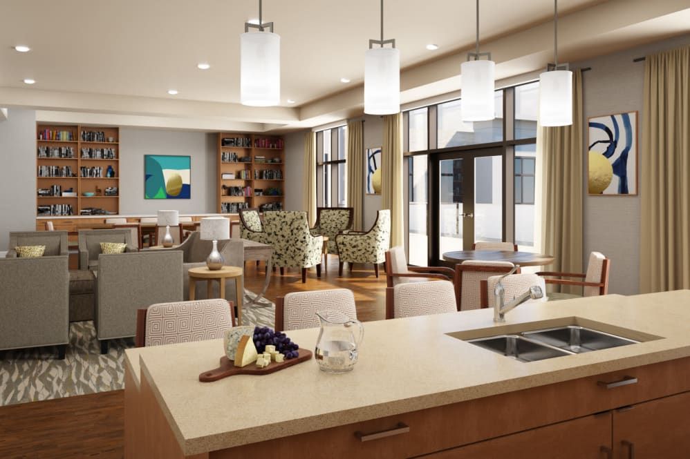 A modern open-concept living space featuring a sleek kitchen island with bar stools, complemented by pendant lighting and contemporary artwork.