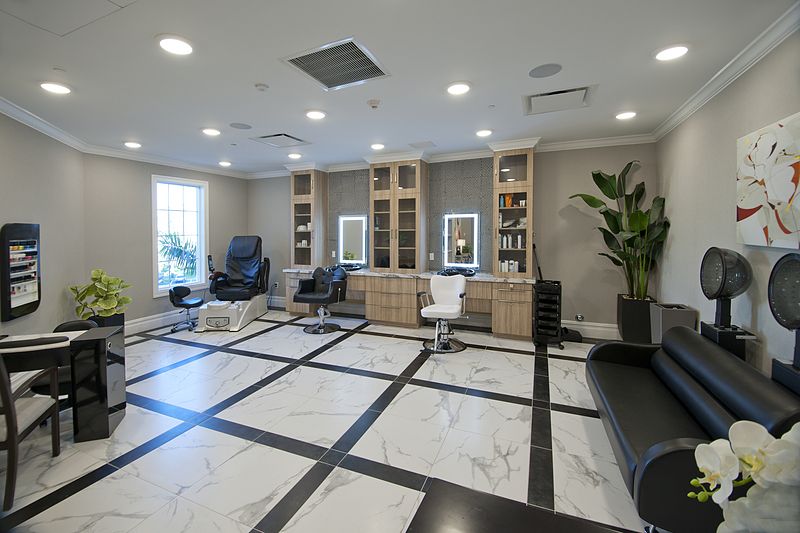 A modern and well-lit salon interior with stylish furniture and a marble floor.