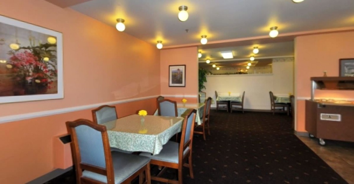 A cozy restaurant dining area with tables and chairs, softly lit by overhead lights.