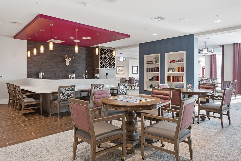 A modern dining and bar area with wooden tables and chairs, featuring stylish shelving and a vibrant red ceiling accent.
