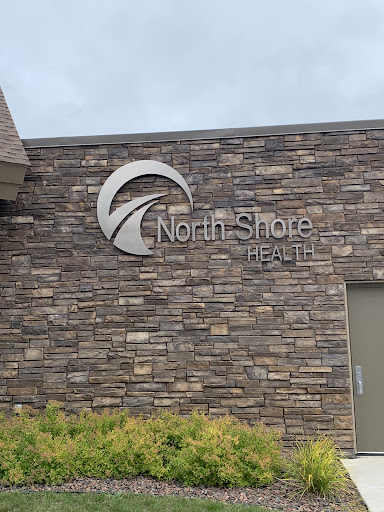 Exterior view of the North Shore Health facility with a stone wall design.