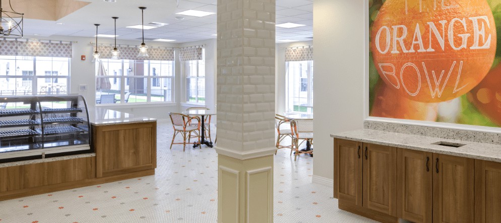 A spacious and bright cafe interior featuring wooden tables, chairs, and large windows.