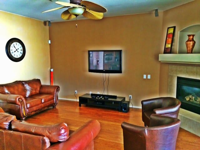 A cozy living room with leather furniture and a wall-mounted television.