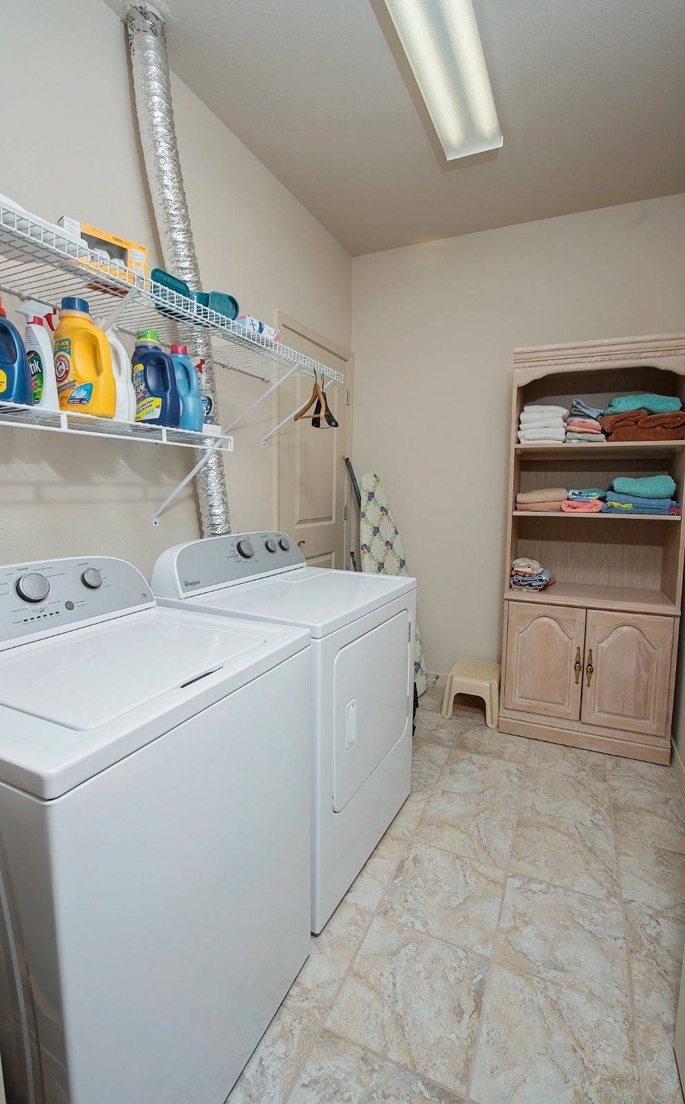 A well-organized laundry room with a washing machine, dryer, and storage shelves.
