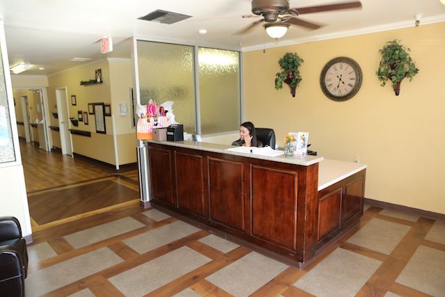 A reception area in an office with a wooden desk, wall clock, and ceiling fan.